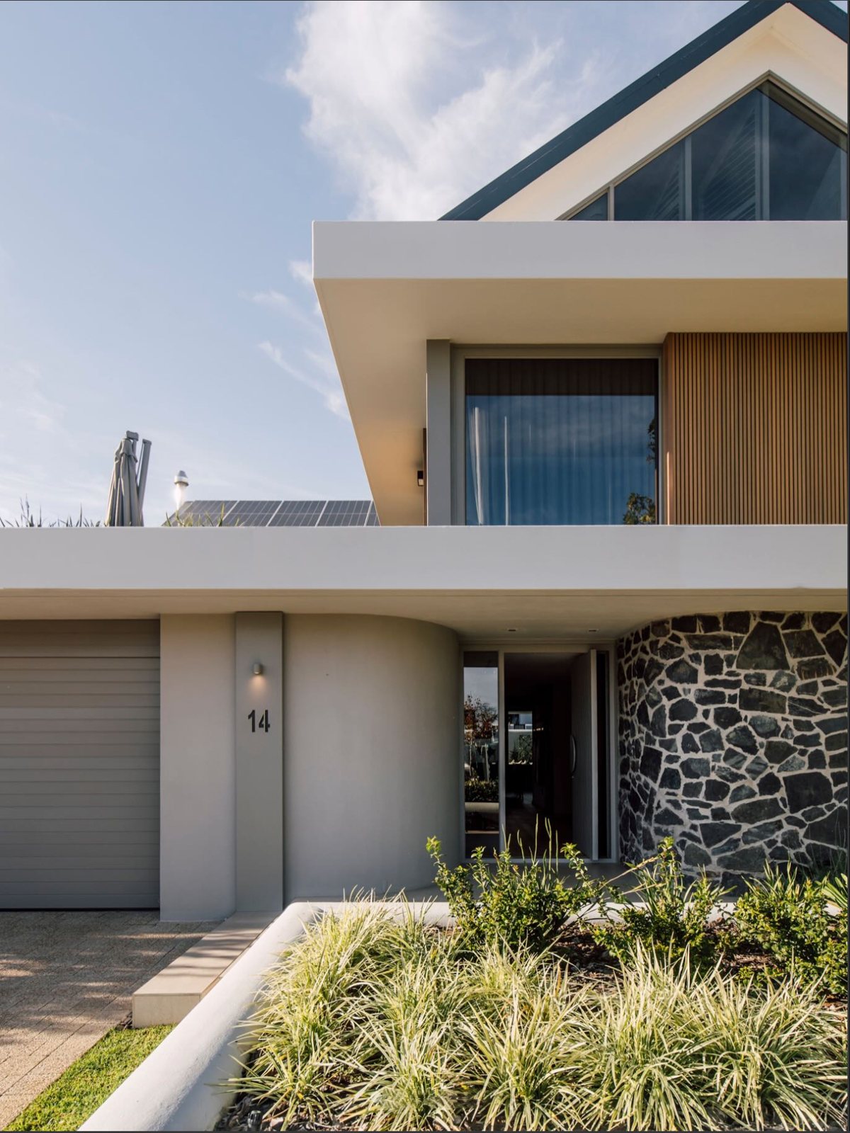 Residential concept with a garage, stone wall and landscaped approach
