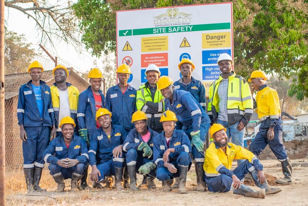Construction team in blue and yellow workwear standing on site.