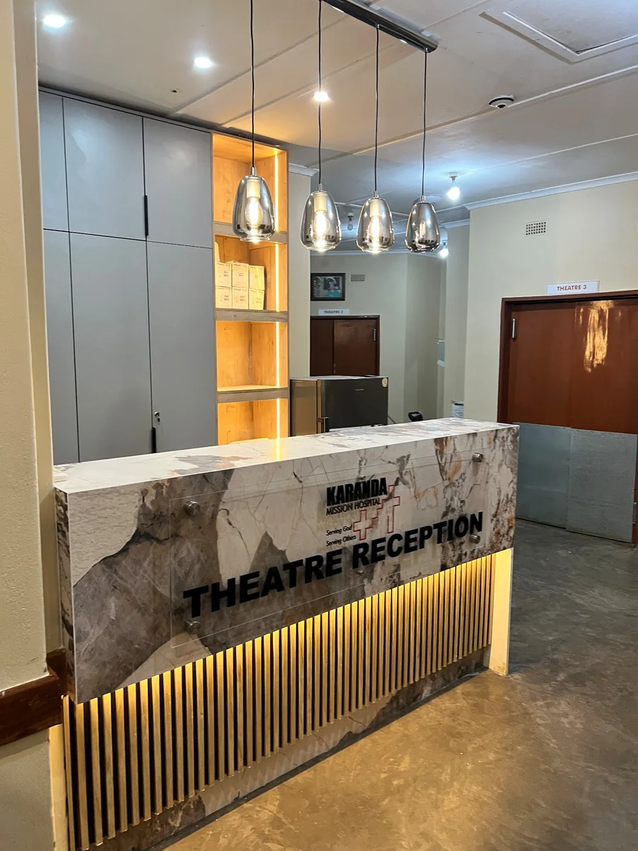 Karanda Mission Hospital theatre reception with illuminated cabinetry, marble-effect counter and hanging pendant lights