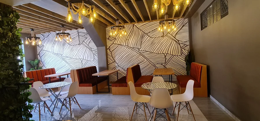 Mr Sadza Eastgate dining interior with patterned wall panels, upholstered seating and warm pendant lighting.