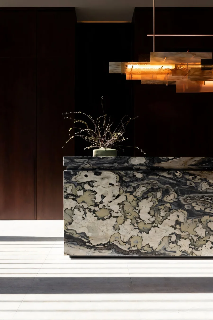 Stone reception counter with warm pendant lighting and a dark feature wall