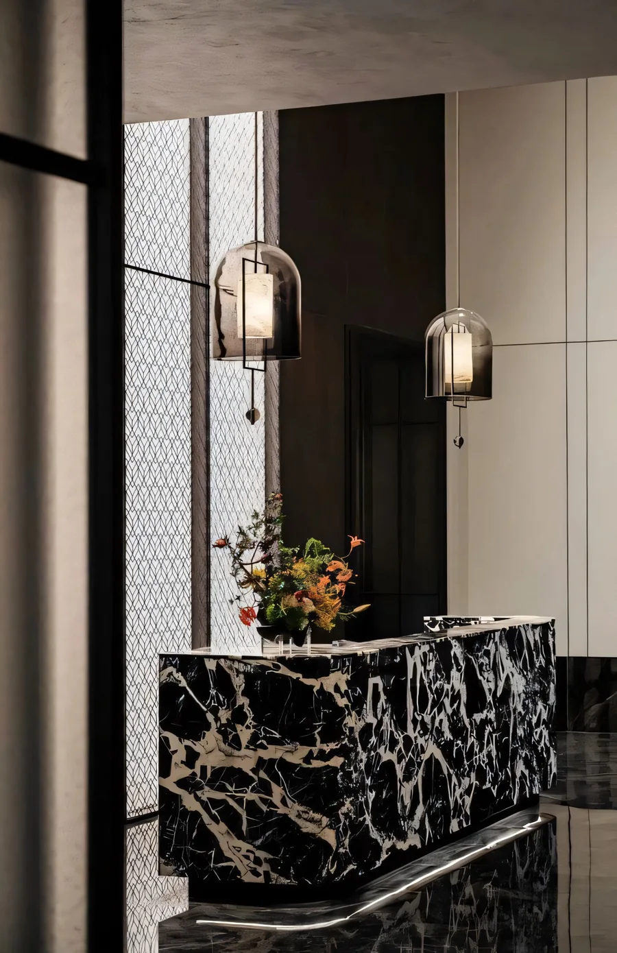 Dark stone reception counter with wall lights, a mirror and floral arrangement