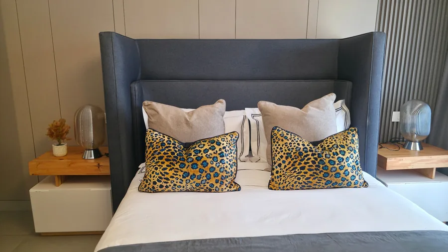 Esfog Lodge, Kadoma: bedroom with a blue upholstered headboard and patterned cushions