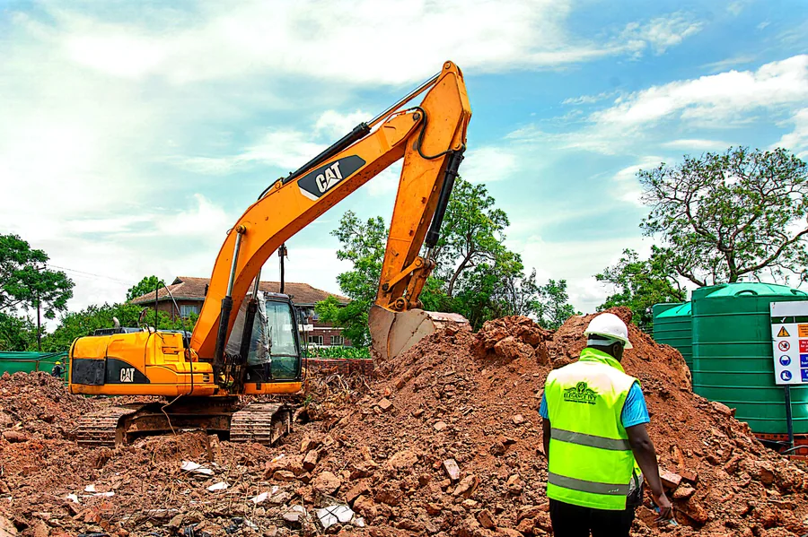 Excavator carrying out earthworks beside an Elegance Ivy team member