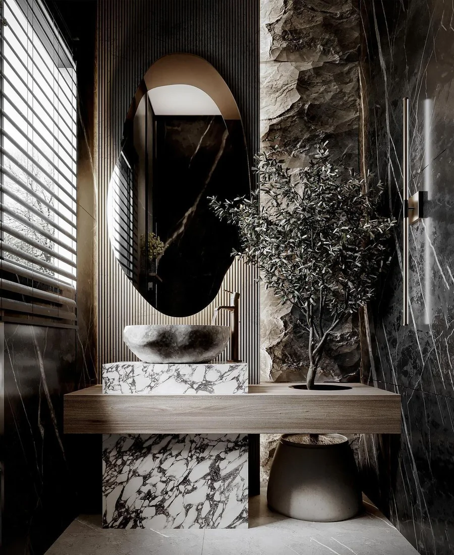 Dark stone washroom design with an arched mirror, textured wall and sculptural basin