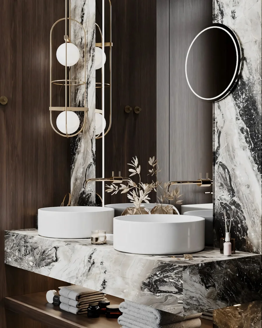 Stone vanity design with twin basins, gold fittings and an oval mirror