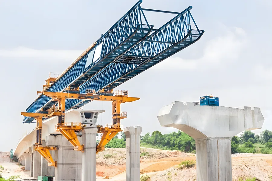 Blue launching gantry spanning concrete piers during bridge construction