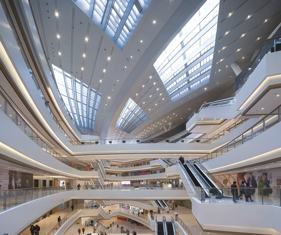 Multi-level commercial atrium with skylights, escalators and curved white balconies